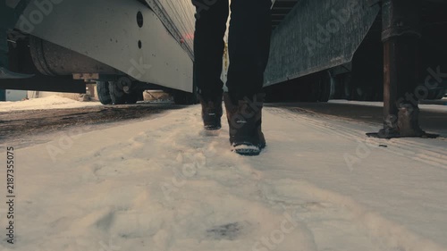 Person walking between parked semi-trailers in winter
