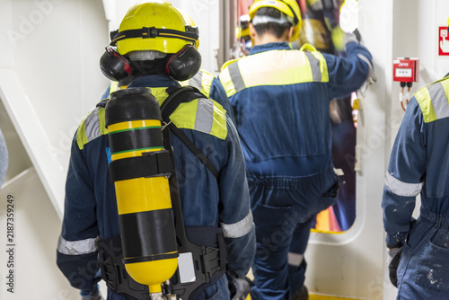 фотографія Group of seafarers moving along the deck during an onboard emergency drill, including crew members wearing protective breathing apparatus and compressed-air cylinders