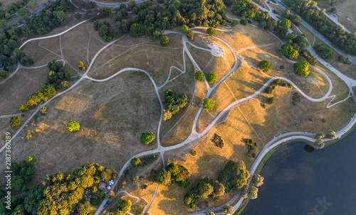 Drone aerial top down view of Olympiaberg hill and winding paths in Olympiapark, Munich, Bavaria, Germany. 