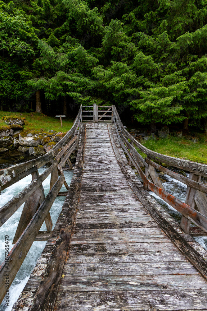 Fototapeta premium A beautiful wooden bridge over a mountain river. A seasonal scenery of Eidsdal village in World Heritage area of Western Norway.