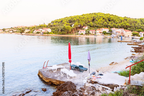 Canvastavla Sun loungers and umbrellas on stone pier overlooking Adriatic bay and town