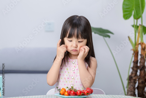 Foto Unhappy Asian little girl refusing to eat vegetables, picky eating and child beh