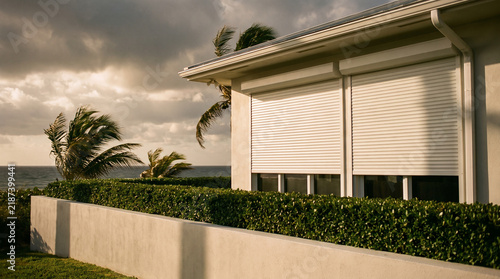 Roller storm shutters closed on a coastal house before a storm