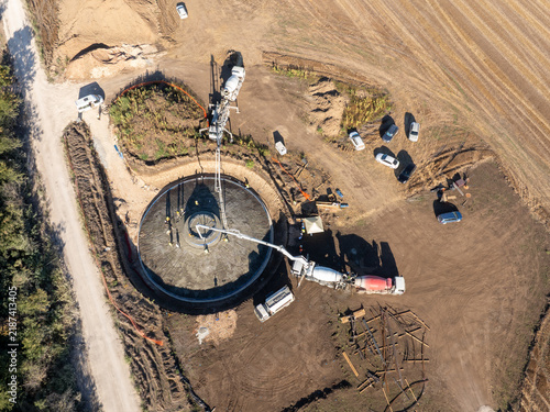 Aerial View of Concrete Pouring at Construction Site for Wind Turbine Foundation, Pump Trucks and Workers Building Renewable Energy Infrastructure
