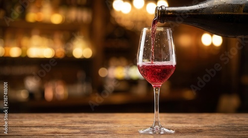 Red lambrusco sparkling wine being poured from a bottle into a wine glass.