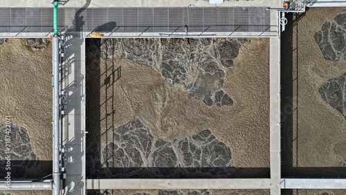 Aerial view of the wastewater treatment plant in Erie featuring large aeration tanks with churning brown water and industrial metal walkways in Erie, Colorado, United States.