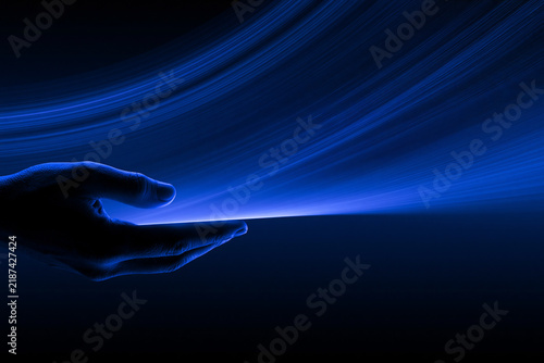 A silhouette of a human hand gently cradles a glowing stream of luminous blue light suggesting energy technology or a mystical connection to the universe