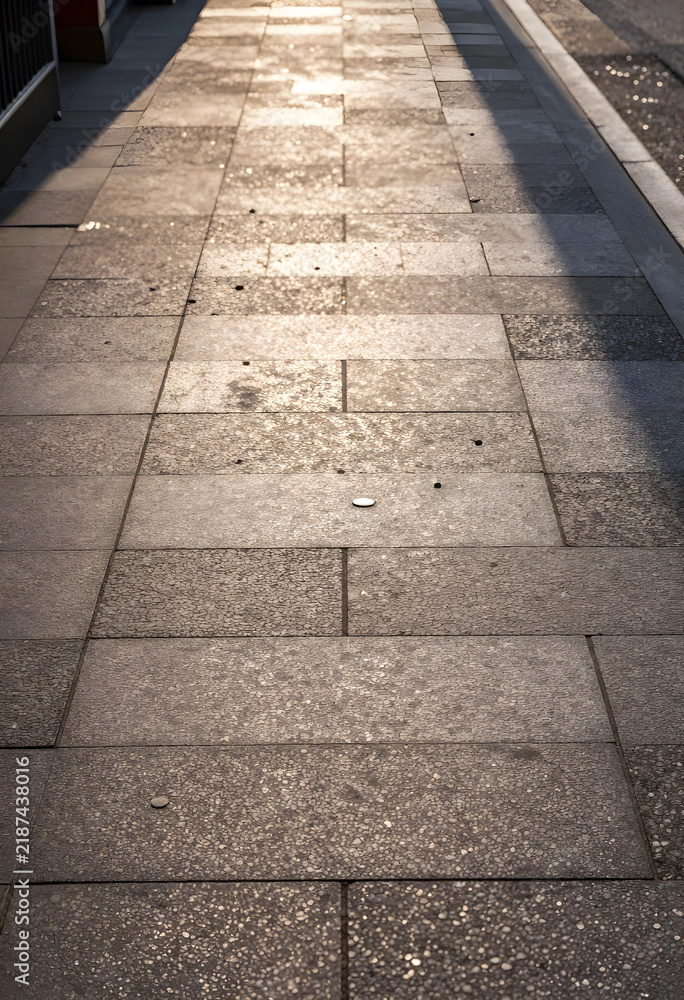Obraz premium Urban commute and city travel, empty sidewalk with golden hour sunlight and long shadows on stone pavement in a modern metropolitan environment