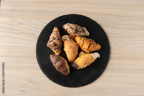 Assorted glazed mini croissants on round black slate plate