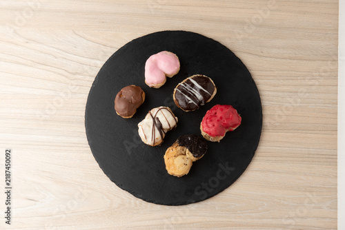 Assorted mini palmier pastries with colorful glazes on slate plate