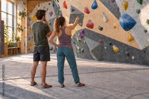 Two climbers discussing holds on an empty indoor bouldering wall