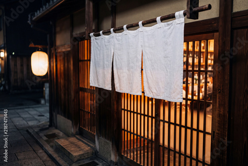 Naklejka 夜の和食店の入口に掛かる白い暖簾と温かな灯り