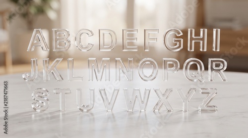 Transparent acrylic alphabet A-Z. Clear 3D capital letters standing on a white marble surface with a soft, bright blurred room in the background.