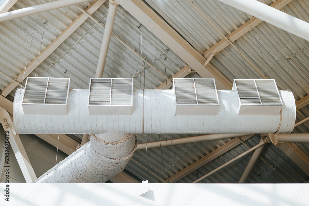 Obraz premium Four ventilation ducts are mounted on a white ceiling in a commercial building. The ducts are equipped with metal grilles for air distribution