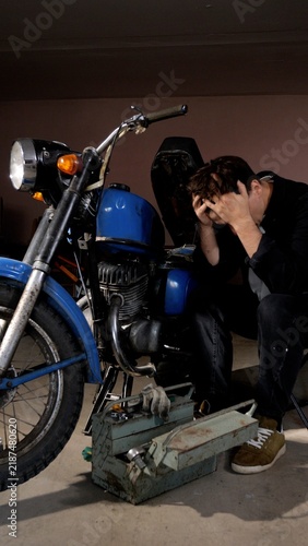 Quadro su tela Man holding his head in frustration while working on a broken vintage motorcycle