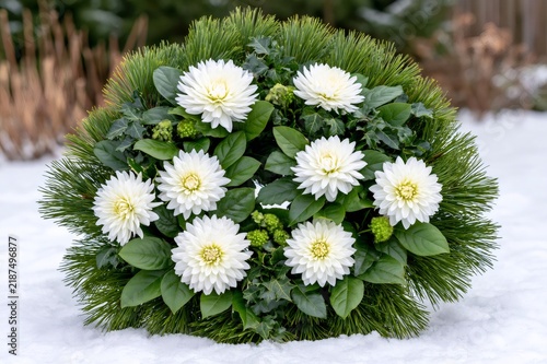 White dahlia funeral wreath resting on snow