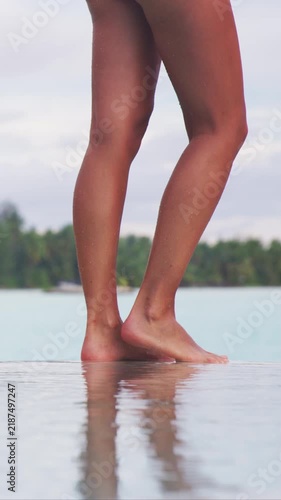 Smooth tanned slim legs banner of sexy swimsuit model lower body woman sunbathing skin by the pool for hair removal laser or cellulite concept. Raw vertical video of real woman.