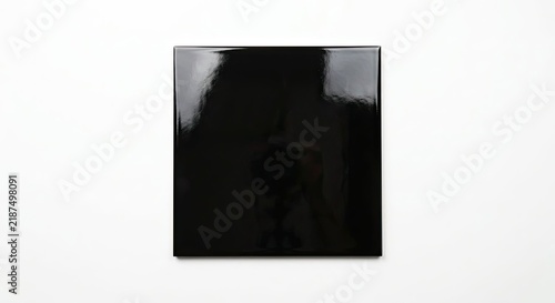 Glossy black square tile on white background.