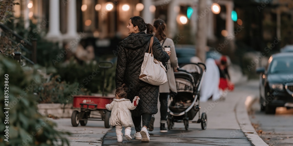 Obraz premium South Asian woman walking on a wet asphalt street during a halloween night, tired expression for parenting and family life media