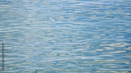 Obraz na plátně Calm blue water surface with gentle ripples reflecting light