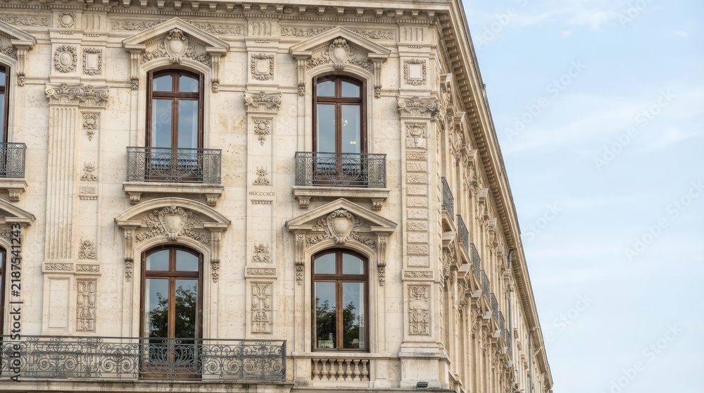 Fototapeta premium A light-colored building with ornate architectural details and multiple windows is captured in a photograph.