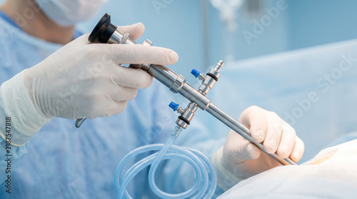 Gloved surgeon holding laparoscope during minimally invasive surgery on patient in operating room