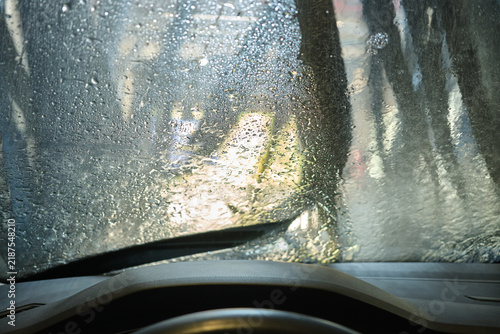 Car windshield covered in water drops inside an automatic car wash tunnel