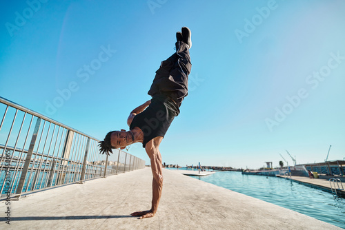 Foto Man performing handstand near water in harbor
