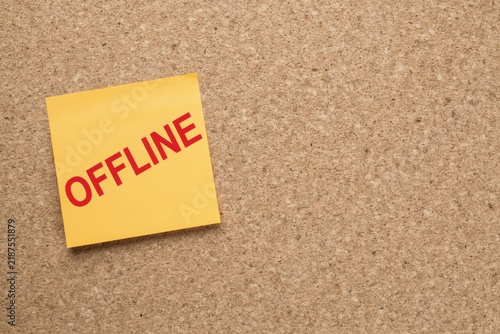 Yellow sticky note with the word offline written in red on a cork board