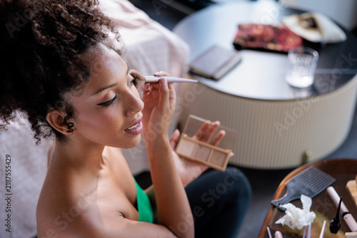 A young woman applying her makeup with a brush