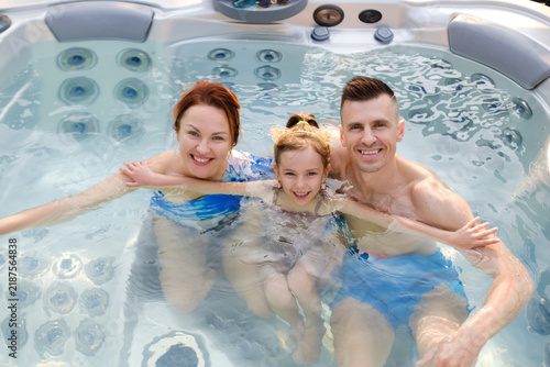 Konstfotografi Family enjoys time together in a hot tub during a sunny afternoon at home while