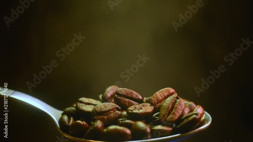 Roasted coffee beans in a vintage metal spoon with smoke video clip. Stock video footage of roasted coffee beans in a vintage metal spoon with gentle smoke on a dark background.