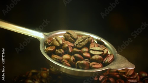 Roasted coffee beans in an antique metal spoon with smoke stock video. Stock video clip of roasted coffee beans resting in an antique metal spoon with light smoke on a dark background.