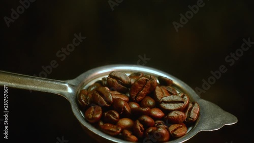 Roasted coffee beans in a vintage metal spoon with smoke stock video clip. footage of roasted coffee beans in an antique metal spoon with gentle smoke on a dark moody background.