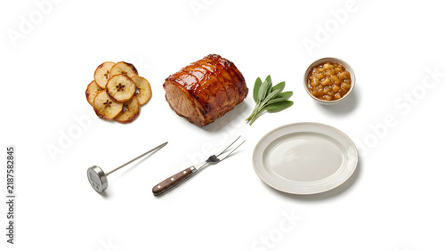 Roasted Glazed Ham Joint With Sliced Cranberry Apples. Serving Fork and Carving Knife Set. Holiday Feast Side Dish Of Sauces and Plate. Traditional Christmas Dinner Food Layout Thanksgiving
