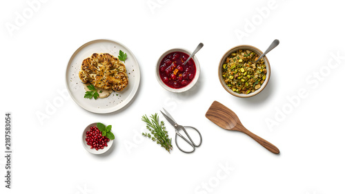 Healthy baked egg florentine sausage breakfast muffins on white ceramic plate with bowls of cranberry sauce and chopping herbs, top view with copy space Thanksgiving
