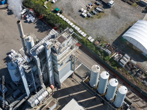 Bayswater, Victoria, Australia - 08 September 2026: Aerial view of the Bayswater downer asphalt plant with industrial machinery, storage silos, steam rising from the stack, and paved yard.