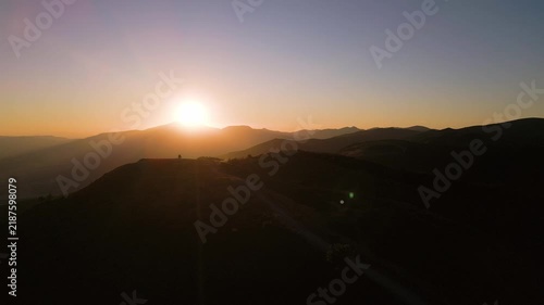 Aerial View of Mountain Sunset Over Silhouetted Peaks and Ridge Road