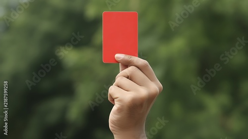 A close-up photograph of a hand holding a red penalty card used in sports to signal an expulsion from the game