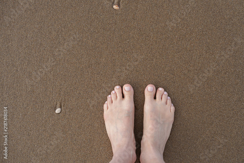 Картината върху платно Bare feet standing on wet beach sand near sea foam