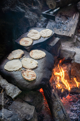 Foto Traditional flatbread cooking on hot stone over open campfire