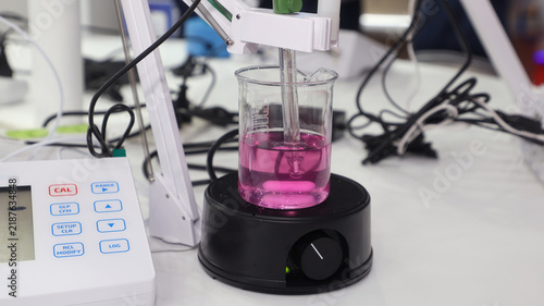 Foto Laboratory digital pH meter and magnetic stirrer with pink solution in a beaker
