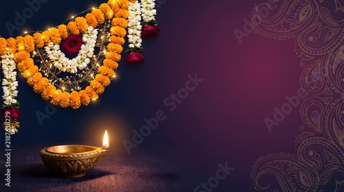 A beautiful glowing diya lamp with traditional marigold flower decorations for the celebration of the hindu festival of diwali