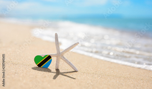 Starfish and the Tanzanian flag on a sandy beach. A resort in Tanzania and Zanzibar.