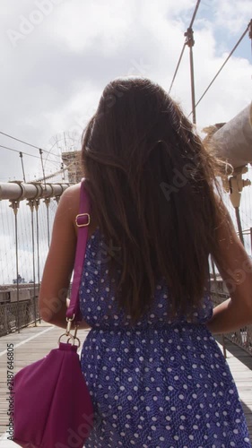 New York City Woman. Young woman on Brooklyn bridge, New York city NYC, Manhattan, USA. Walking young professional in blue dress.