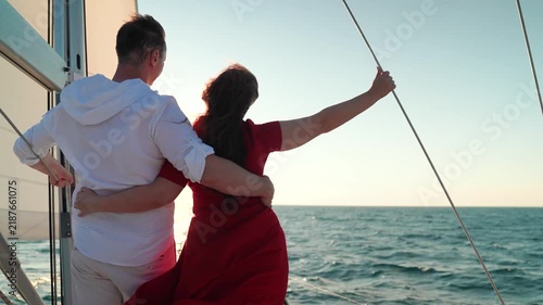 Yacht under sail glides through sea, man woman in love embrace on deck. Sail towards your dreams adventures. Captain Man woman travel on yacht under white sails. Sea voyage with free wind. Romance sea