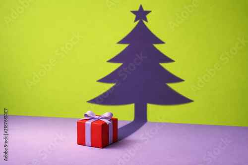 Christmas gift box casting tree shadow on colorful background