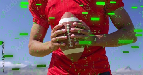 Gripping laced football at chest, athlete in red jersey posing outside with green overlay