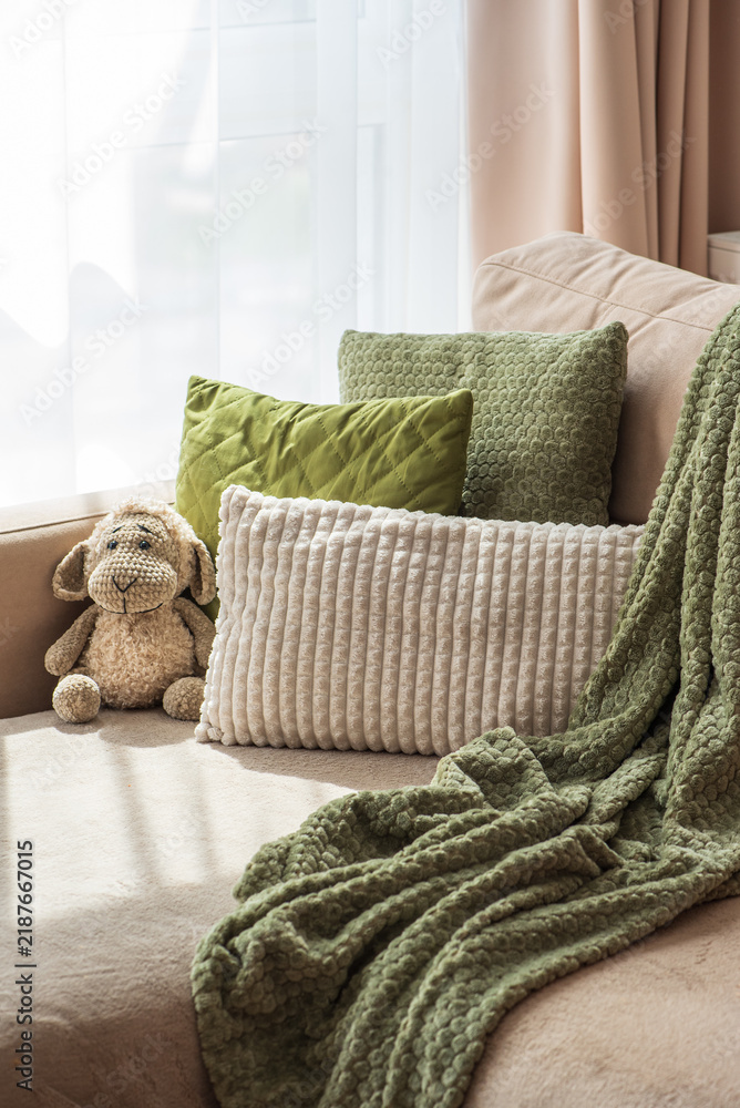 Obraz premium Cozy living room scene with plush pillows and a soft blanket on a sofa