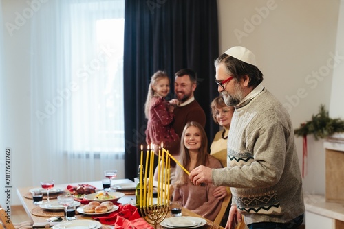 Obraz na plátně Jewish family celebrating hanukkah, lighting menorah candles